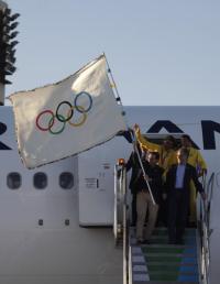 リオデジャネイロの国際空港に五輪旗とともに到着したパエス市長（手前左）（ロイター＝共同）