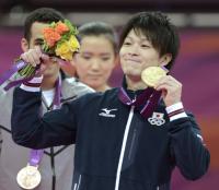 体操男子個人総合で優勝し、金メダルと花束を手に笑顔を見せる内村航平（共同）