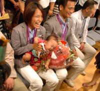 抱きかかえた赤ちゃんが大泣きし、笑う金メダリストの松本。右は銅メダリストの海老沼