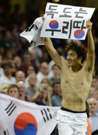 「独島はわれわれの領土」と書かれたメッセージボードを掲げた韓国の朴鍾佑