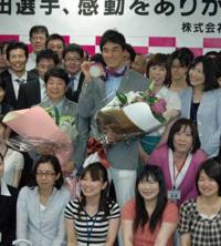 大勢の社員に囲まれ笑顔でメダルを掲げる松田（中央）。同左は久世コーチ
