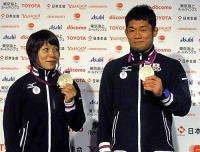 重量挙げの三宅（左）は「メダルを持って」と言われ、柔道の平岡をまねるように持つ